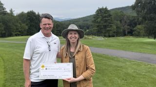 Two individuals hold a check for a donation to the AIAVT Scholarship fund