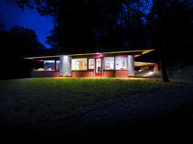 Modern, angular, brightly colored night-time view of small residence
