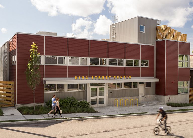 2-story rectangular urban building with red metal siding