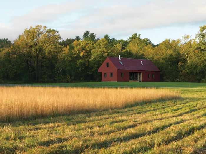 Simple red painted house on the edge of a field