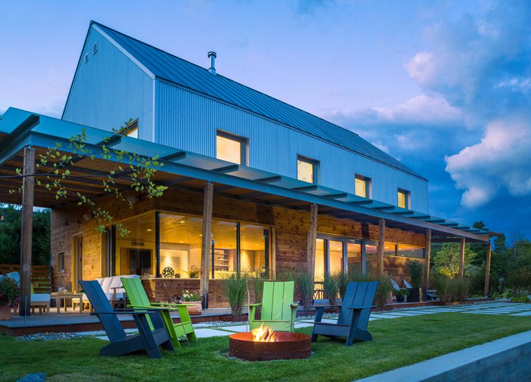 corrugated metal, gabled form with wrapping porch and glazed wood 1st story